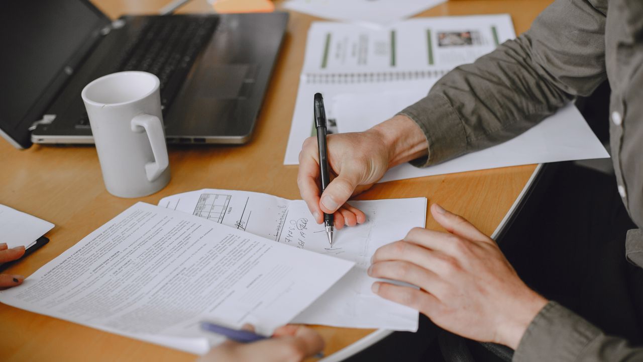 Persona firmando un formulario en su escritorio