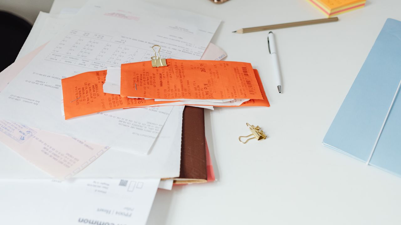 Documentos con un clip naranjo sobre un escritorio